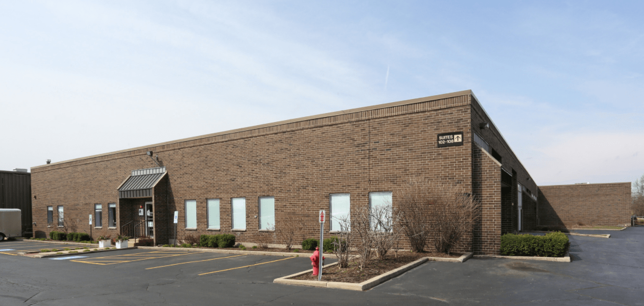 An industrial warehouse made of brick and a parking lot, Cawley CRE