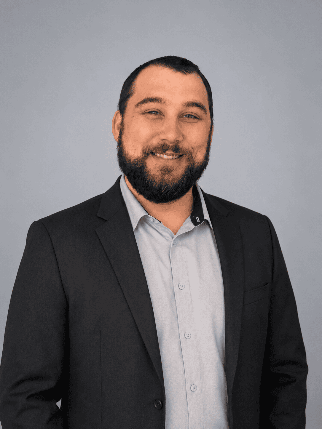 Professional portrait of a smiling man in a suit and light shirt.