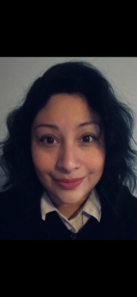 Portrait of a woman with curly black hair and a friendly smile.