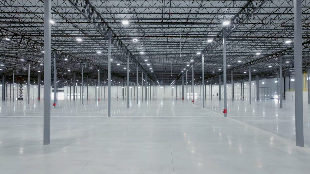 Spacious industrial warehouse interior with high ceilings and bright lighting.
